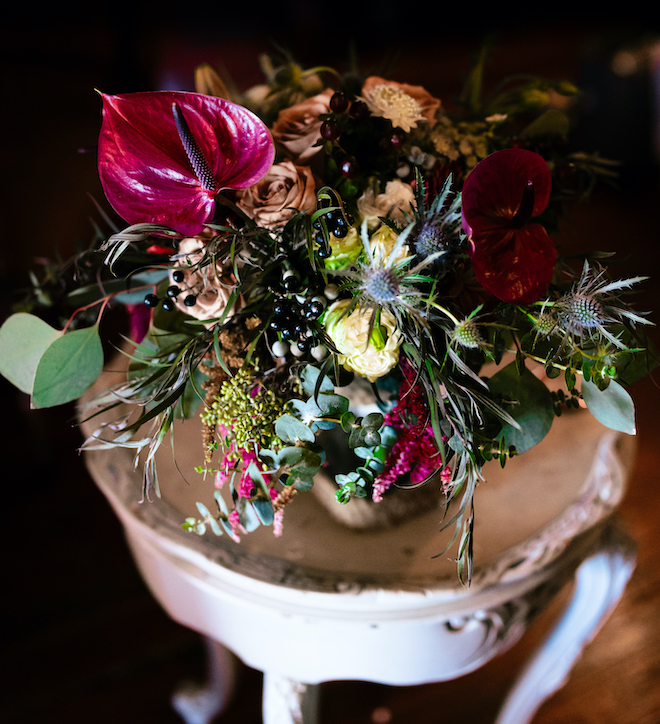 Burgundy flowers and greenery detail the floral arrangements for the bohemian wedding. 