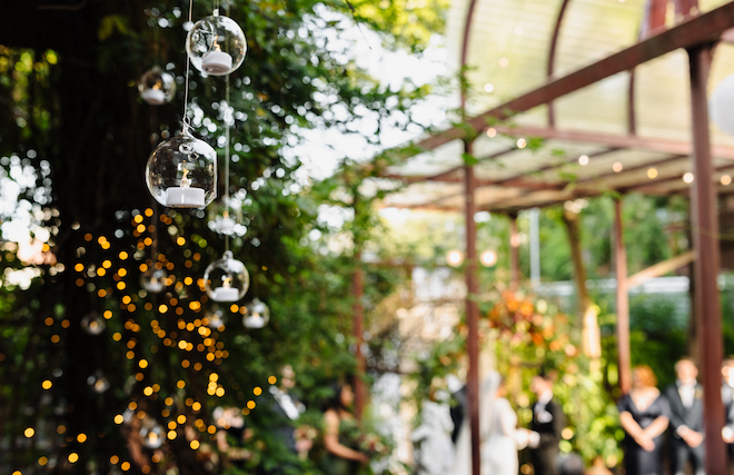 Glass candle holders hang from the tress at the bride and groom's wedding reception.