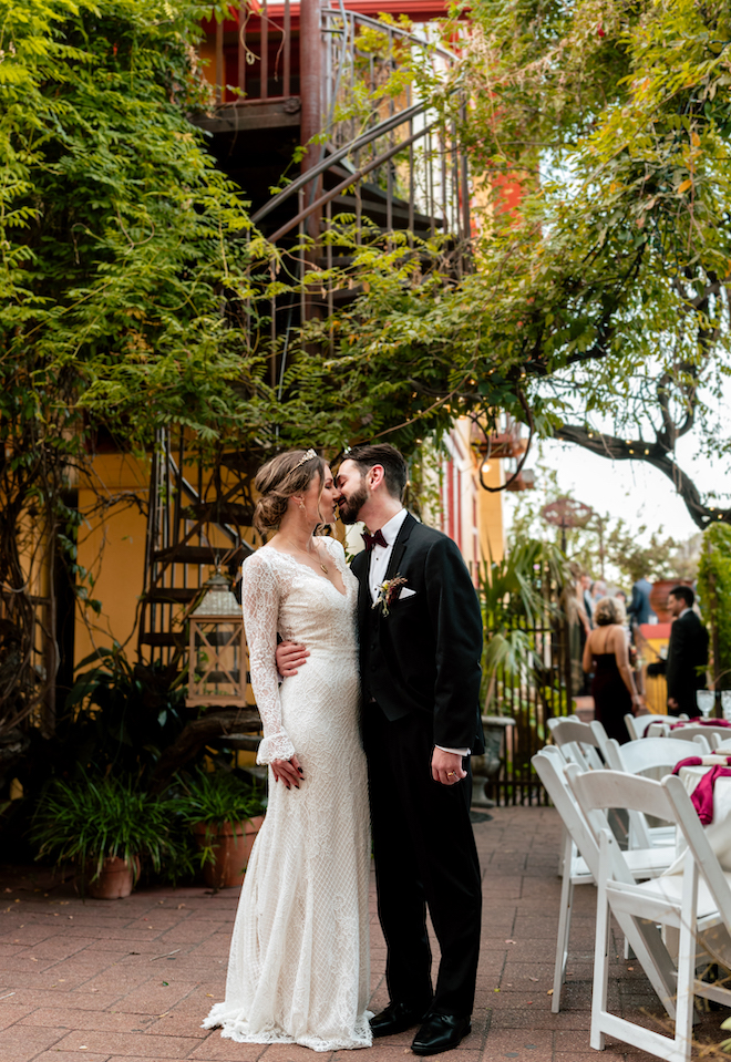 The bride and groom share a kiss at their outdoor wedding reception.