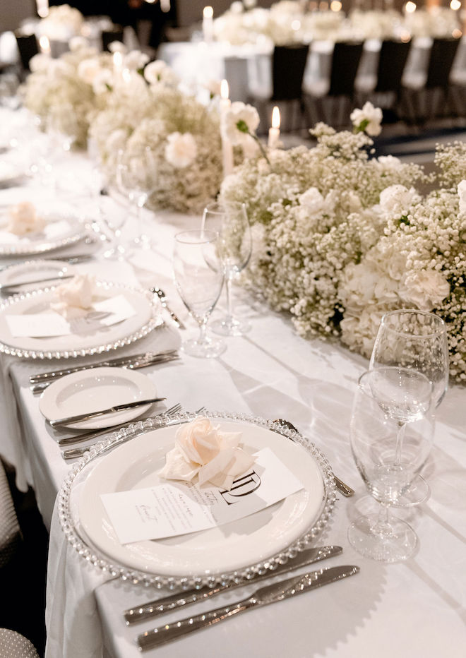 The reception tables are decorated with table setting, candlelight and white flowers for this old-Hollywood wedding editorial. 