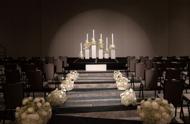 Baby's breath and white roses line the altar at the wedding ceremony at the wedding venue, Hyatt Regency Baytown - Houston.