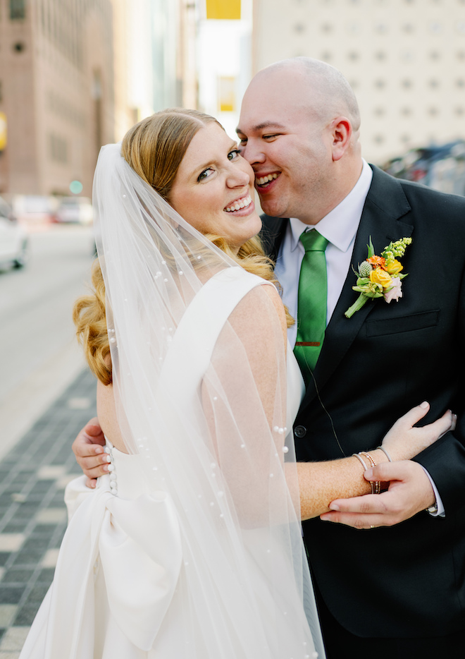 Bride and groom smile outside of Downtown Houston wedding venue, The Ballroom at Bayou Place.