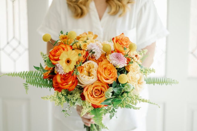 The bride bouquet with orange, yellow and pink florals. 