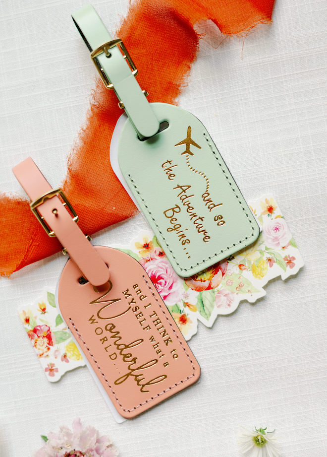 Pink and green luggage tags that say "and so the Adventure Begins..." and "and I Think to Myself what a Wonderful World..."
