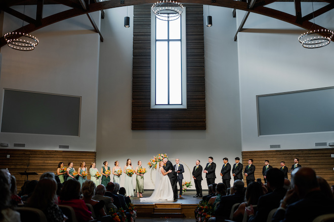 The bride and groom kissing at the altar during their wedding ceremony. 