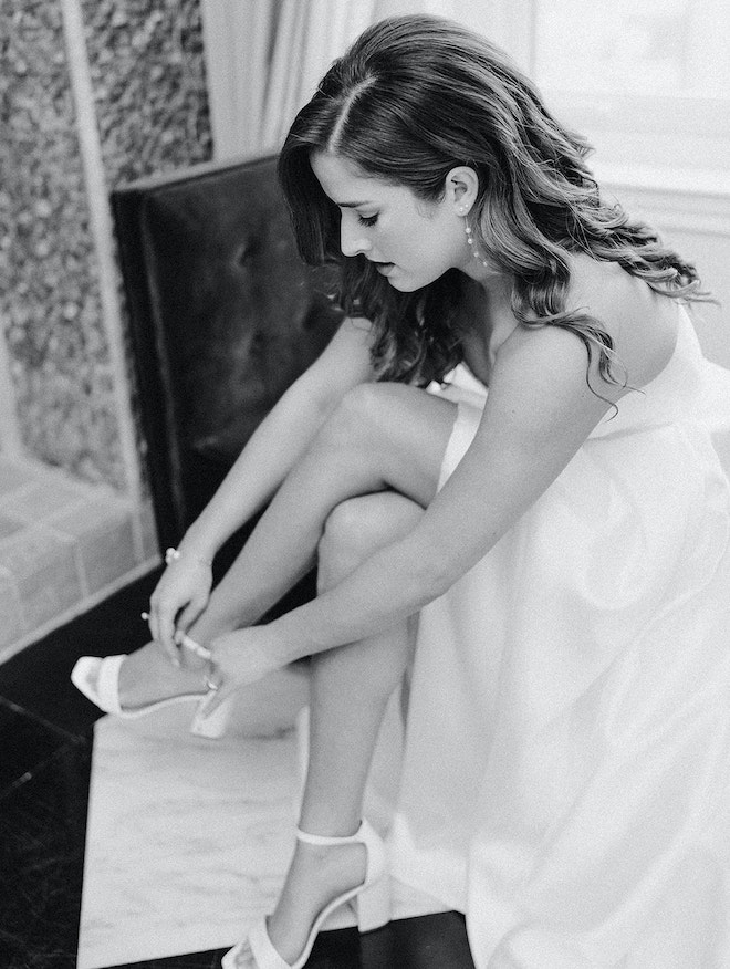 The bride puts on her shoes before her wedding ceremony in Houston.