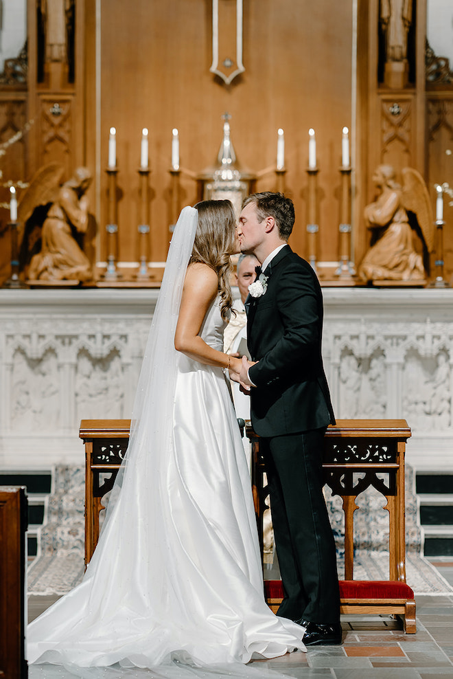 The bride and groom share a kiss at the alter after exchanging vows in a Houston church. 