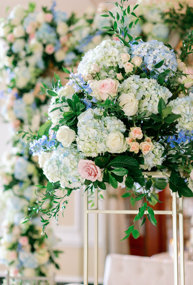 A floral centerpiece with blue hydrangeas, pink roses and greenery by Plants N' Petals. 