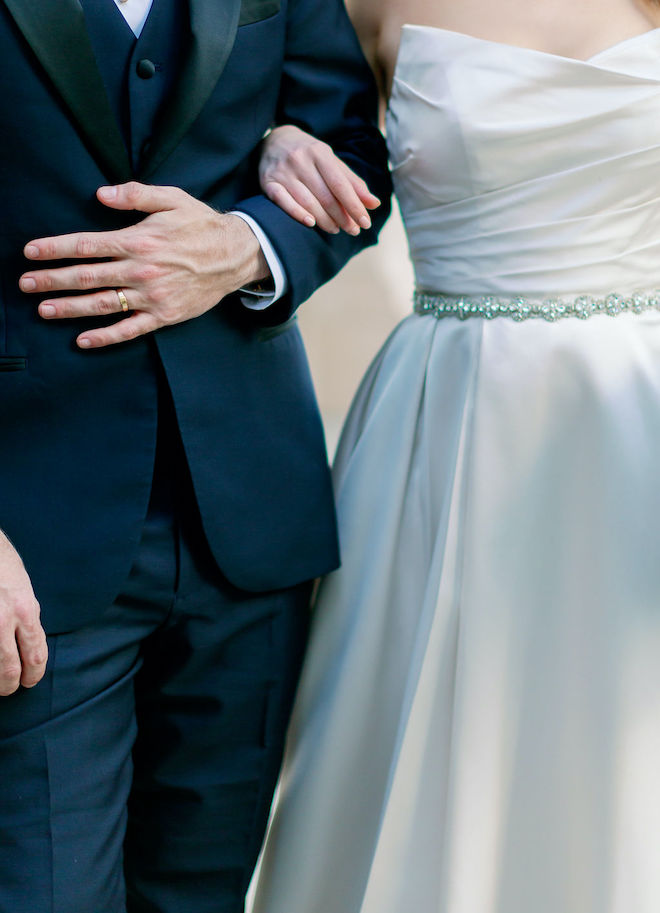 The bride and grooms arms linked.