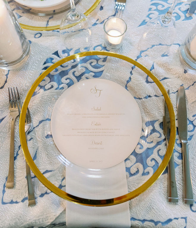 A clear plate with a clear rim sitting on a blue and white printed tablecloth. 