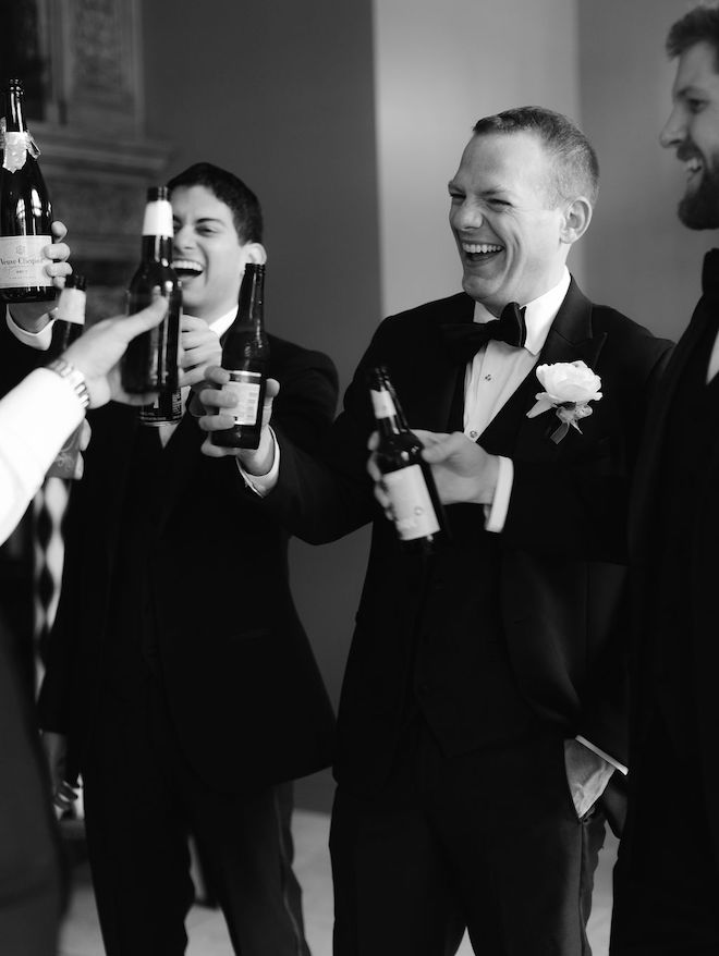 The groom and his groomsmen toasting with beers. 