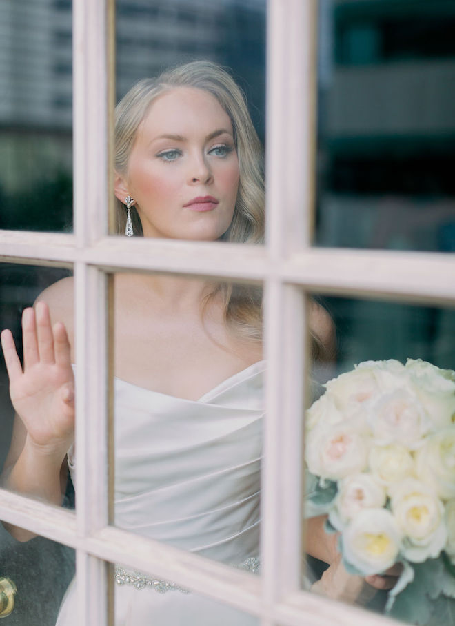 The bride looking out the window of the Crystal Ballroom at the Rice. 