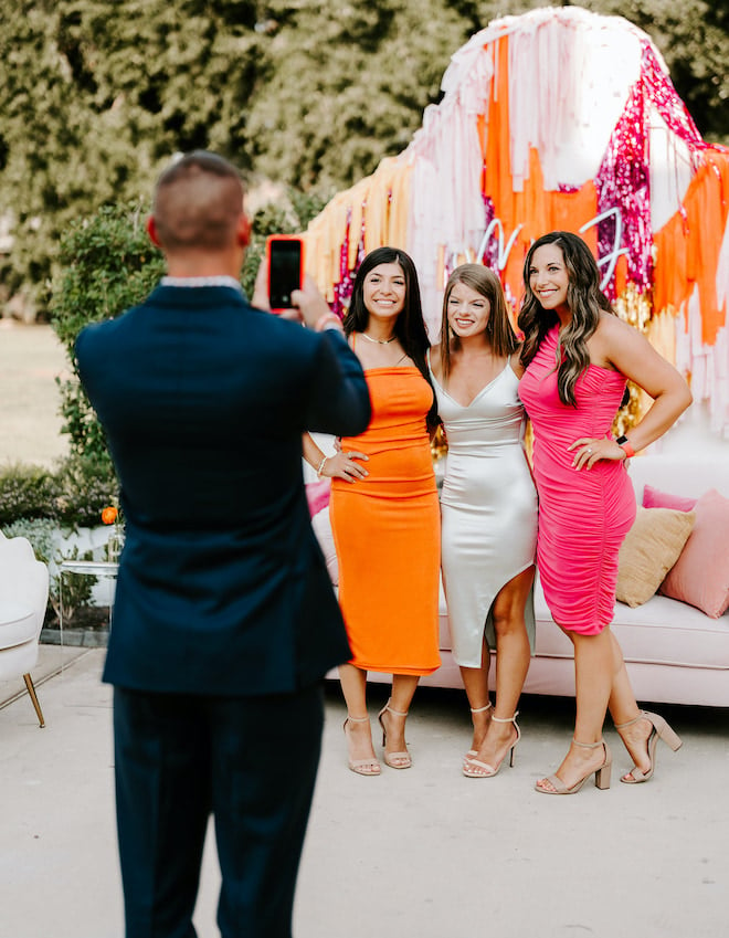 Three girls posing for a picture wearing cocktail attire. 