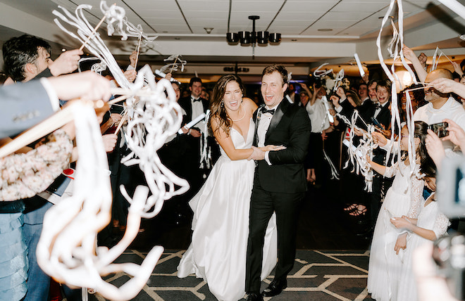 The bride and groom exit their wedding reception with a streamer send-off. 