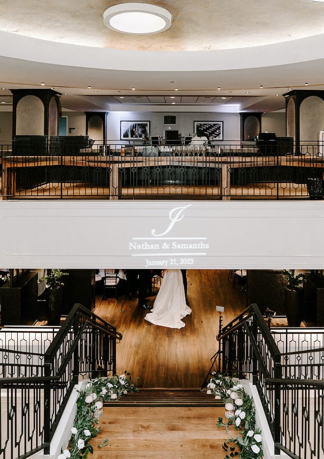 The bride and groom's wedding date and names are projected on the stair case at their wedding reception at the Magnolia Hotel Houston.