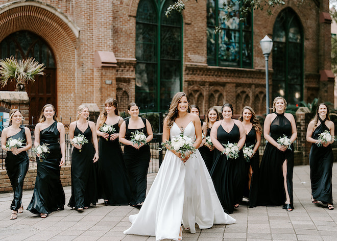 The bride smiles with her bridesmaids outside of a church in Houston. 
