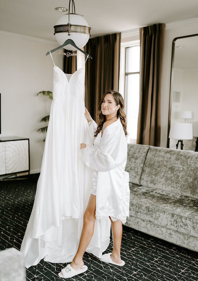 The bride poses next to her strapless wedding gown from Belle Ame Bridal. 