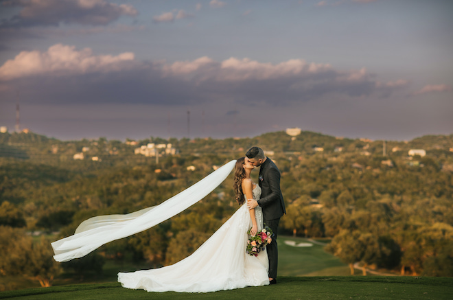 The bride and groom share a kiss overlooking the Texas hill country at Omni Barton Creek Resort and Spa. 