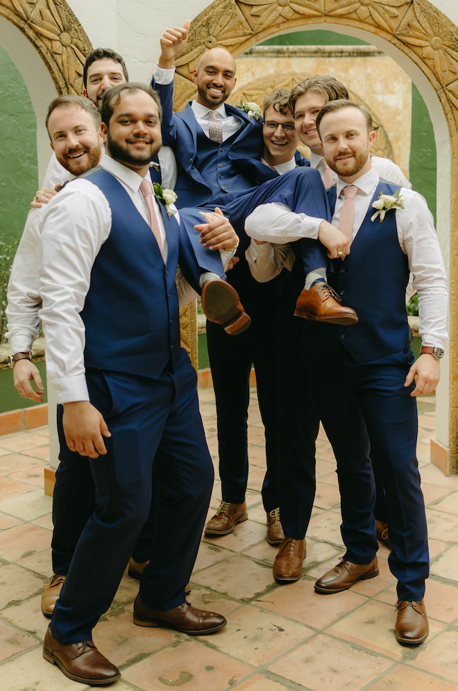 The groomsmen hold the groom above their shoulders before his traditional wedding ceremony.