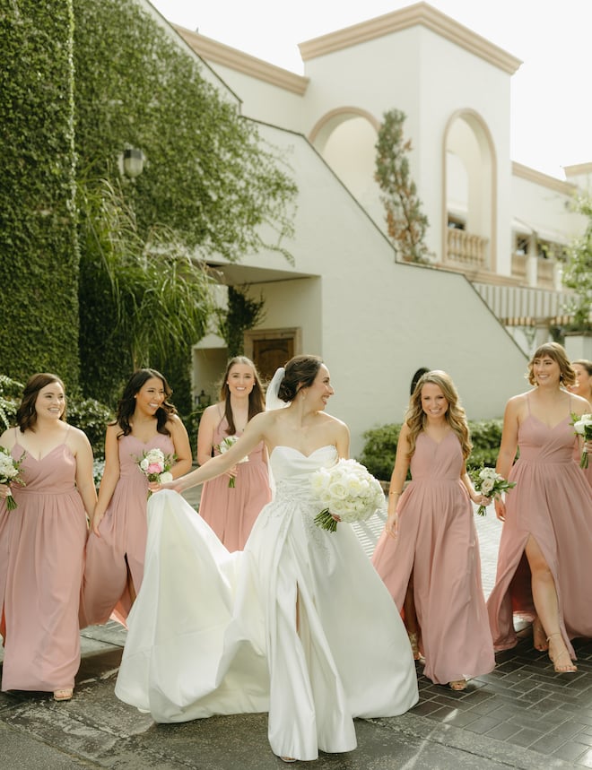 The bride and her bridesmaids walk outside the Bell Tower on 34th before her white, blush and red Indian-fusion wedding day. 