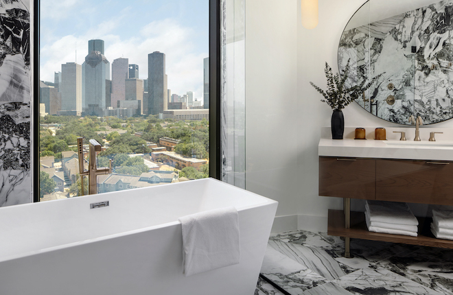 The hotel bathrooms at the new Houston wedding venue, Thompson Houston, has window views of downtown. 
