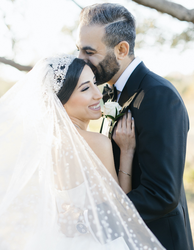 The groom kisses the bride on the cheek at their wedding celebration at the Omni Houston Hotel. 