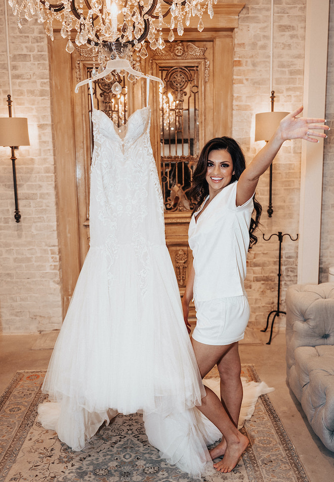 The bride smiles next to her designer gown by Ines di Santo on her wedding day at The Astorian.