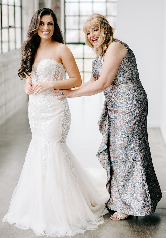 The mother of the bride zips her bride into her wedding dress by Ines di Santo.