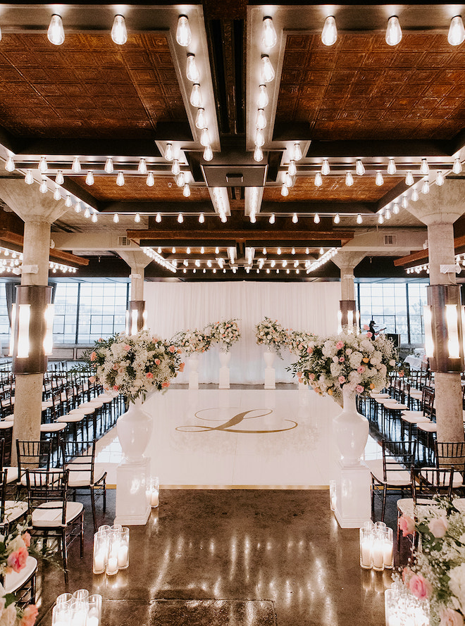 Pink, white and greenery florals by Plants N' Petals decorate the ceremony space at the downtown wedding venue, The Astorian. 