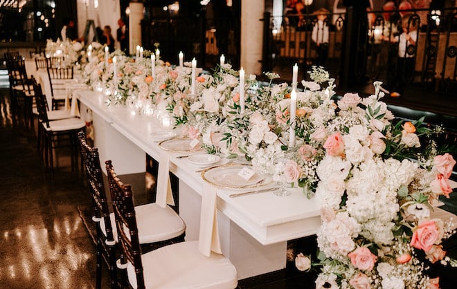 Pink and white flowers, greenery and candles decorate the reception tables for the bride and groom's celebration at The Astorian. 