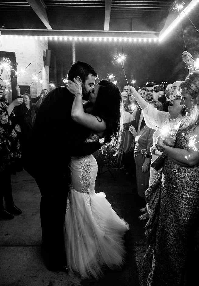 Bride and groom kissing during a sparkler send-off at Houston wedding venue The Astorian