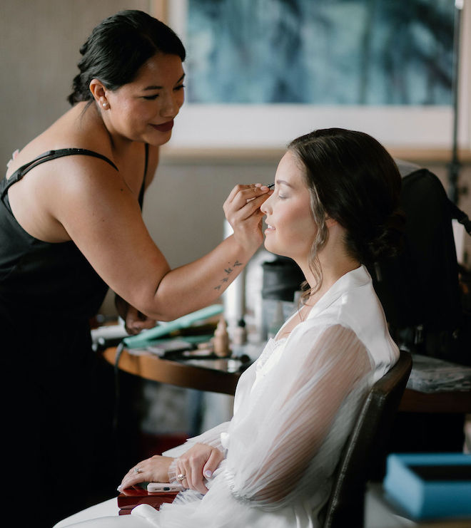 A makeup artist putting eyeshadow on a bride. 