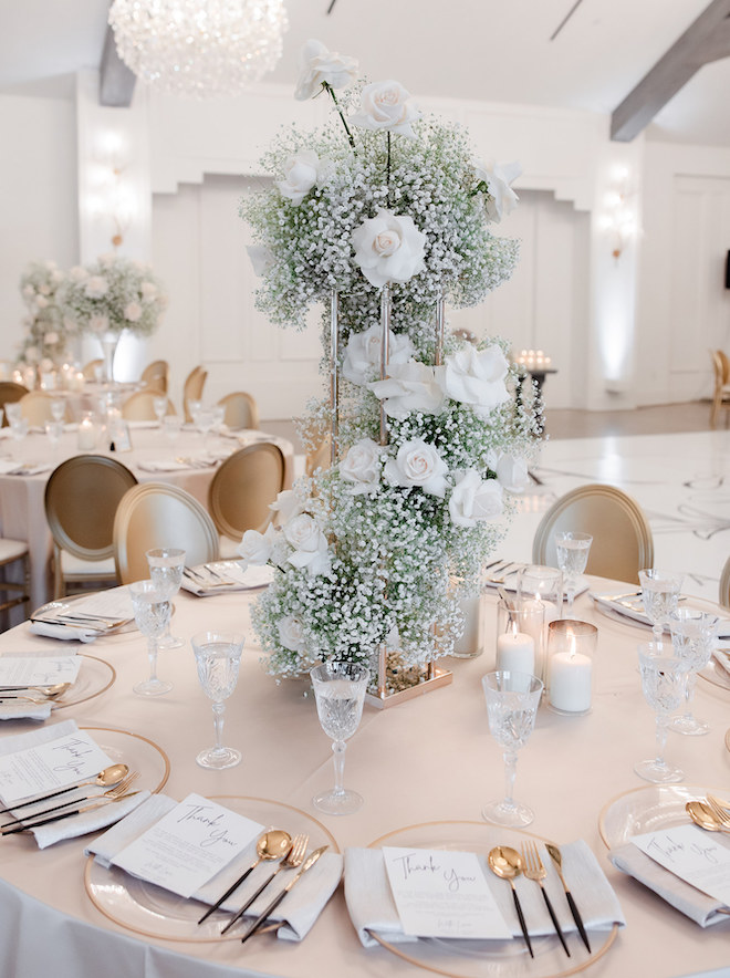 A floral centerpiece of white roses and baby breath at the reception table.