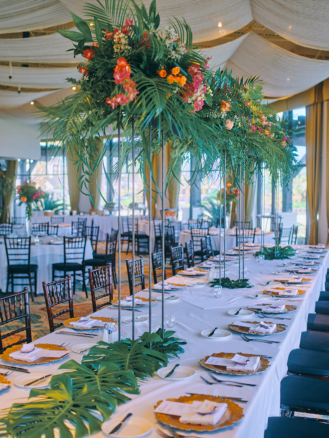 Tropical floral centerpieces on a long reception table. 