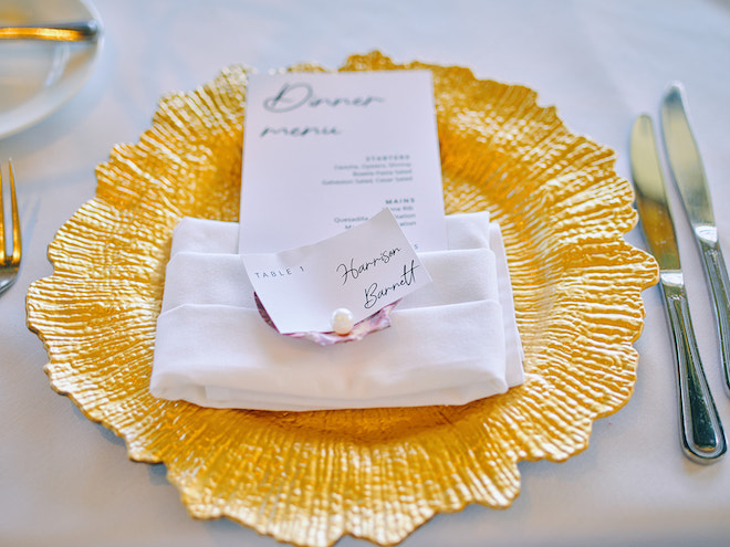 White napkin, name tag and menu on a gold dinner plate. 
