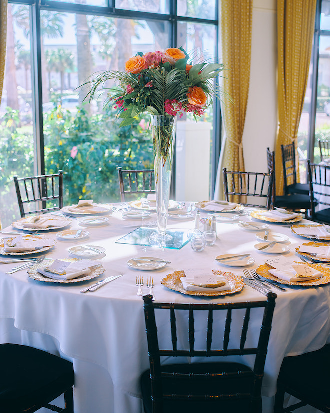 A tropical floral centerpiece on a white round table. 