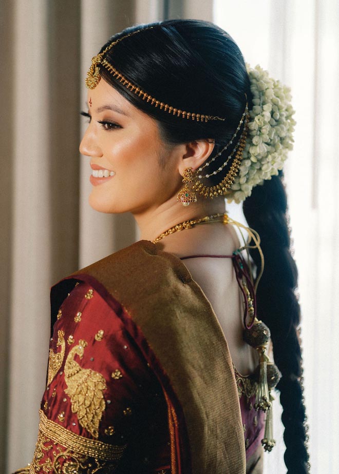 The bride smiles looking over her shoulder wearing traditional Indian wedding attire.