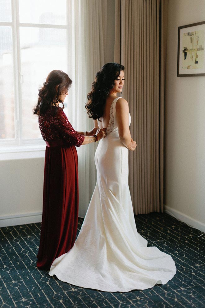 The bride's mother zips her into her dress before her ballroom reception in Downtown Houston.