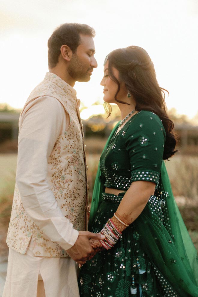 A bride and groom holding hands outside facing each other. 