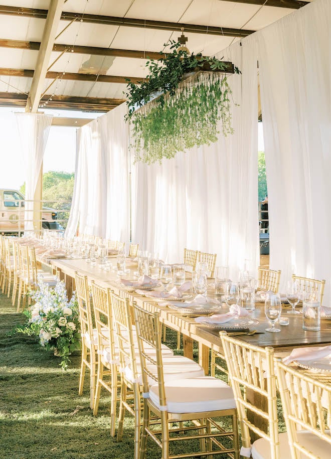 Chandeliers with greenery hang over the reception tables at the Brenham ranch wedding.