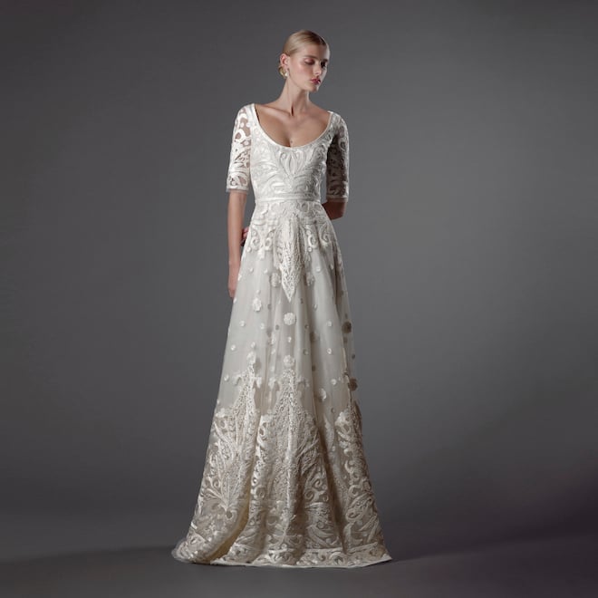 The mode wears an ivory gown featured in Naeem Khan's 2024 Fall Bridal Collection detailed in hand pleated ribbon.