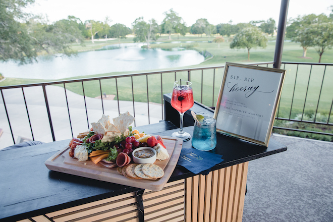 A charcuterie board and cocktails against the backdrop of the Pine Forest Country Club golf course. 