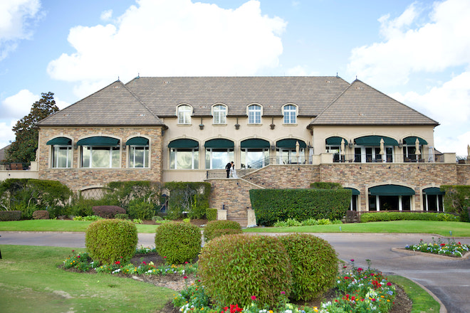 The exterior of The Royal Oaks Country Club with a couple kissing on the staircase. 