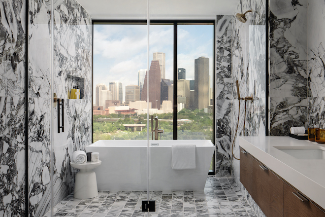 A marble bathroom with a view of downtown at Thompson Houston. 