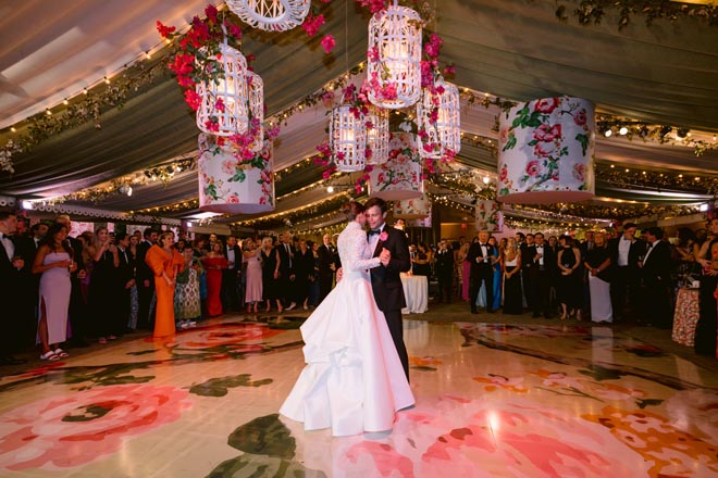 The bride and groom dancing on the floral print dance floor. 