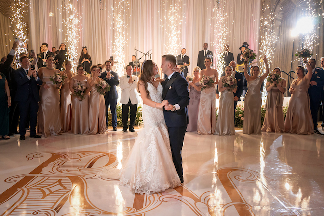 A bride and groom dancing on a custom monogrammed dance floor with sparklers behind them. 