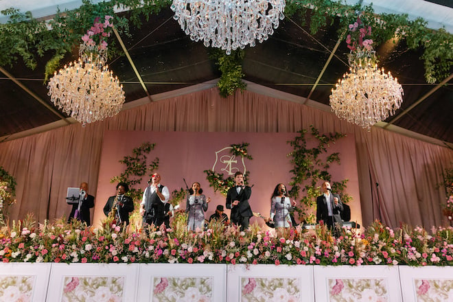 A wedding band on a floral filled stage performing. 