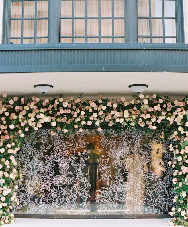 A neutral hued floral archway with floral print on the windows outside of Corinthian Houston. 