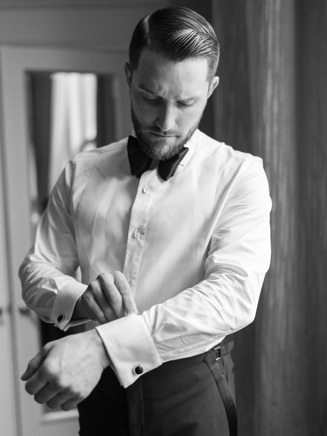 The groom buttoning his shirt before the ceremony. 