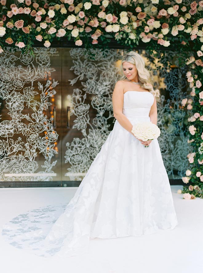 The bride standing in front of the floral entryway in front of Corinthian Houston.